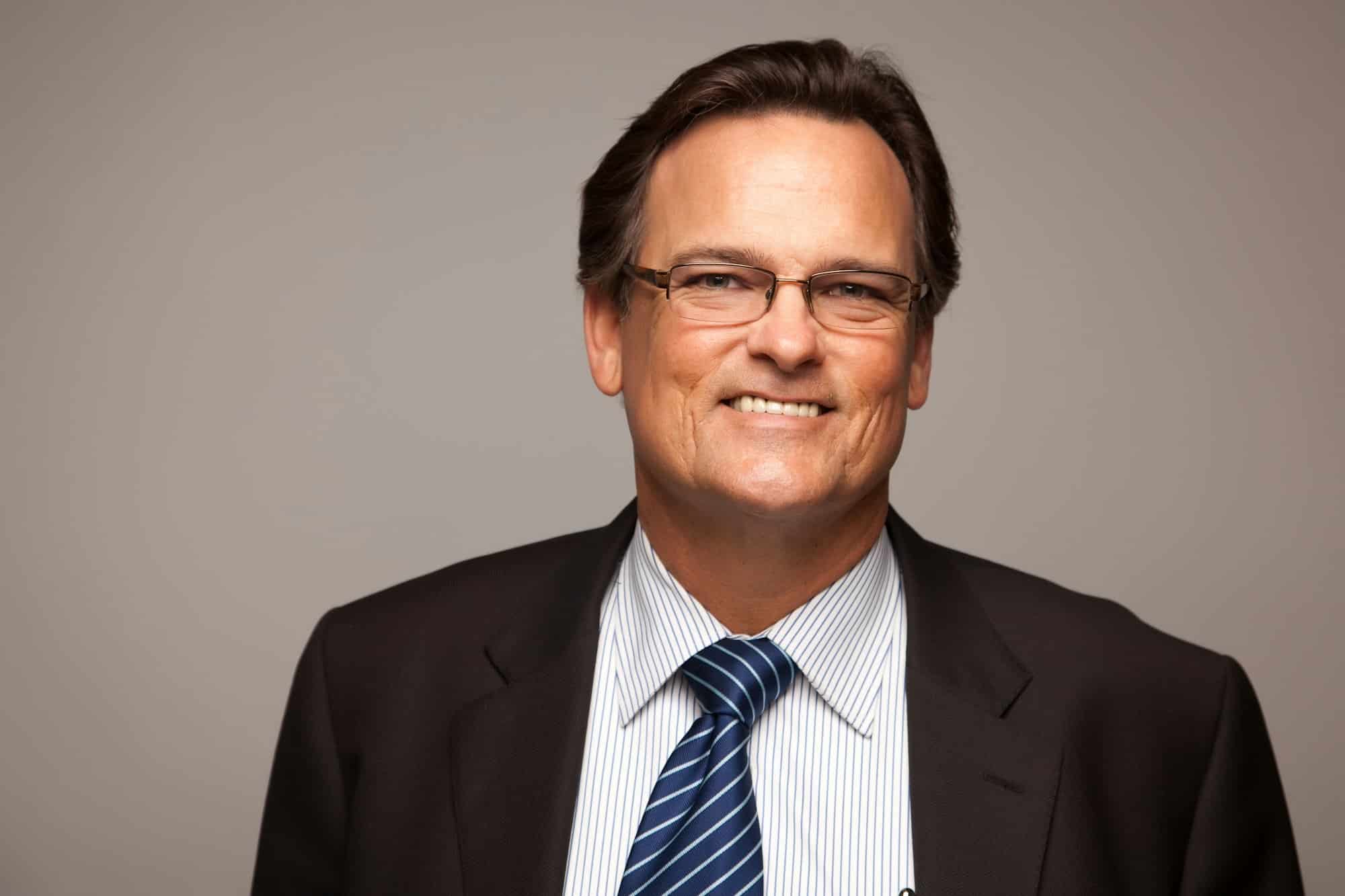 Handsome Businessman Smiling in Suit and Tie Isolated on a Grey Background.